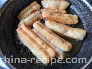 霜糖油条,炸的过程中用筷子不断的翻动，让油条可以受热均匀。
