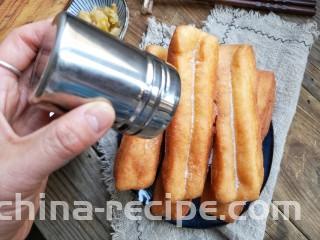 霜糖油条,装盘后趁热筛上糖粉。