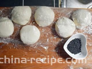 紫薯烧饼,将醒发好的面复揉成光滑的面团后，根据紫薯丸子的数量，将面团分成相同数量的面剂子，并准备适量的黑芝麻。