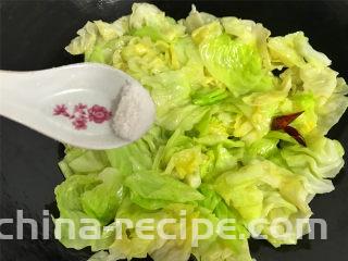 炝炒手撕包菜,快速翻炒均匀，让菜叶都沾上油汁后，加入适量的盐。
