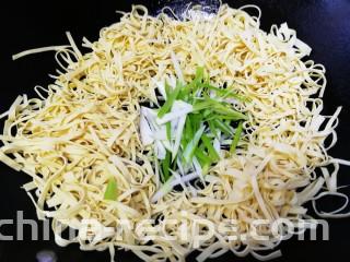 凉拌千张,挑去花椒大料，把千张丝放入炸完油的凉锅里，放入葱丝。