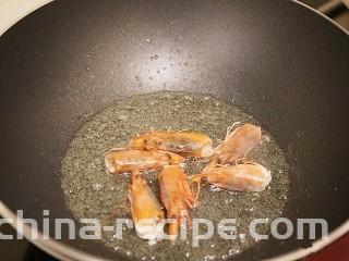 鲜虾粉丝煲,锅中倒入少许油，油热后，将虾头放入锅中煸炒出虾油，然后把虾头取出扔掉锅中留下虾油。