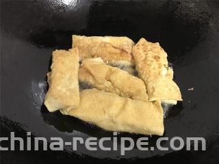 豆腐皮包肉,转中火，一面煎好后翻面再煎另一面，直至两面煎至金黄色。