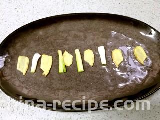 粤式清蒸鲈鱼,把姜片和葱段摆放在鱼盘上。